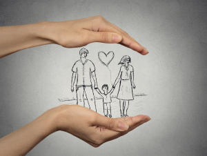 woman's hands protecting happy family, grey wall background