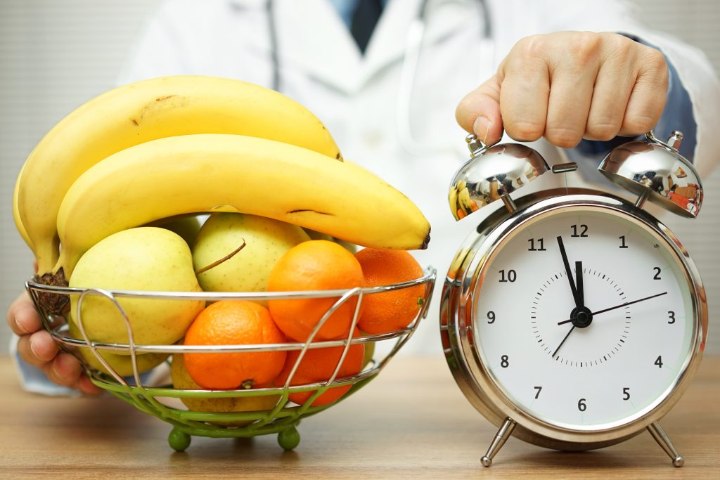 doctor is showing clock and fruit to patient to change eating habits know