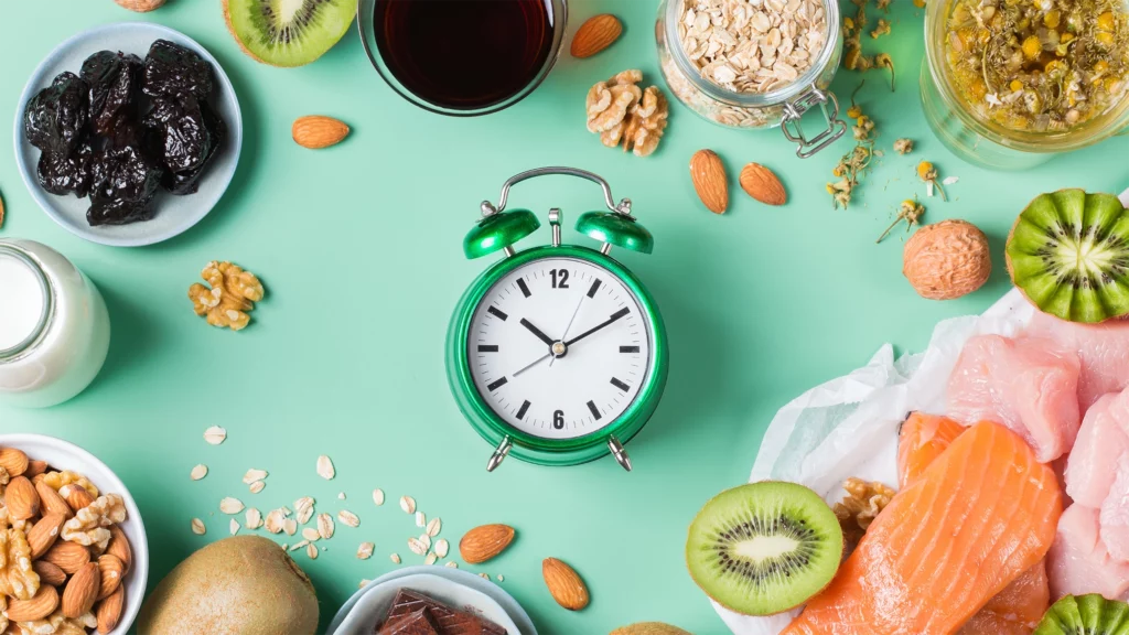 Healthy Shift Worker items on an aqua background, including an alarm clock and foods to help with sleep inclugin kiwi, nuts, oats, salmon, chamomile